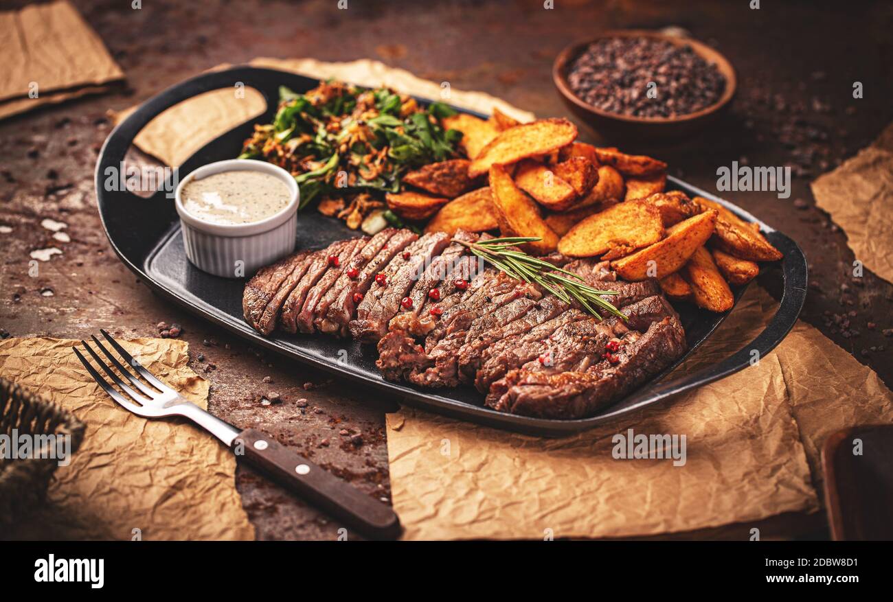 Bistecca alla griglia a fette Rib eye con salsa al pepe e patate fritte dorate Foto Stock