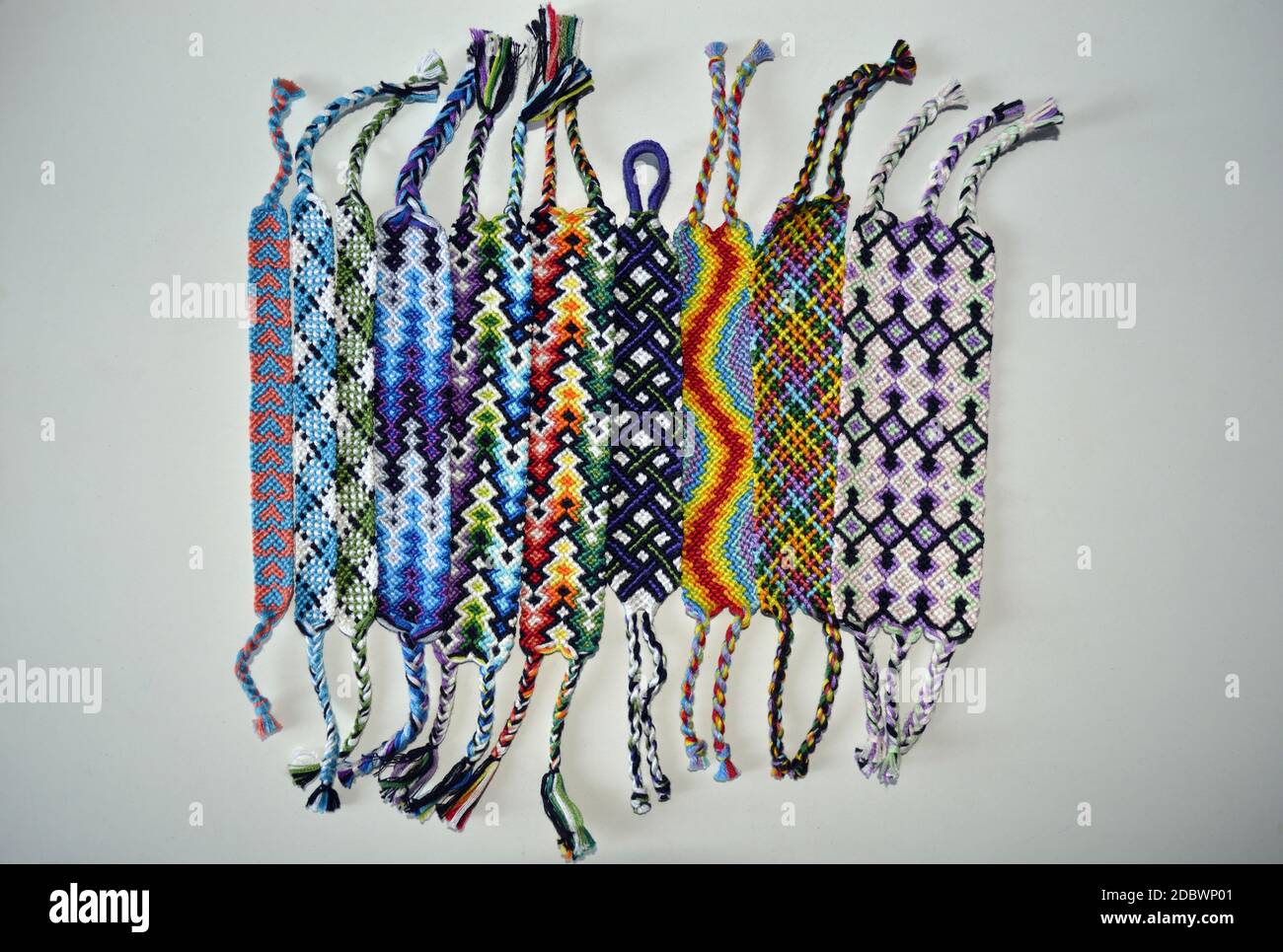 Bracciali di amicizia intrecciati multicolore fatti a mano con filo lucido  ricamato nodi su sfondo chiaro Foto stock - Alamy