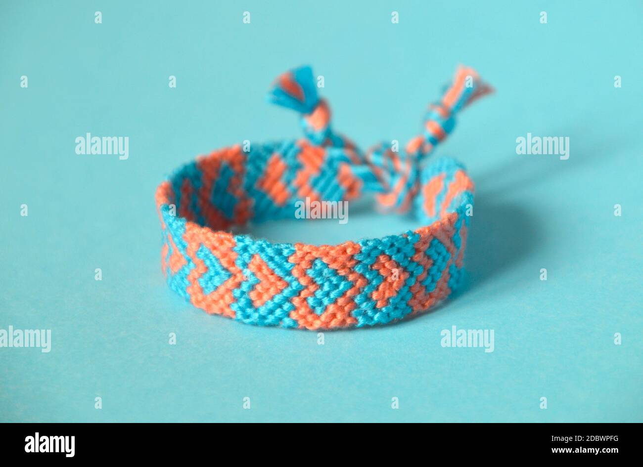 Fuoco selettivo del bracciale di amicizia intrecciato, fatto a mano di filo  e nodi, con motivo di cuore blu, rosa. Su sfondo blu Foto stock - Alamy