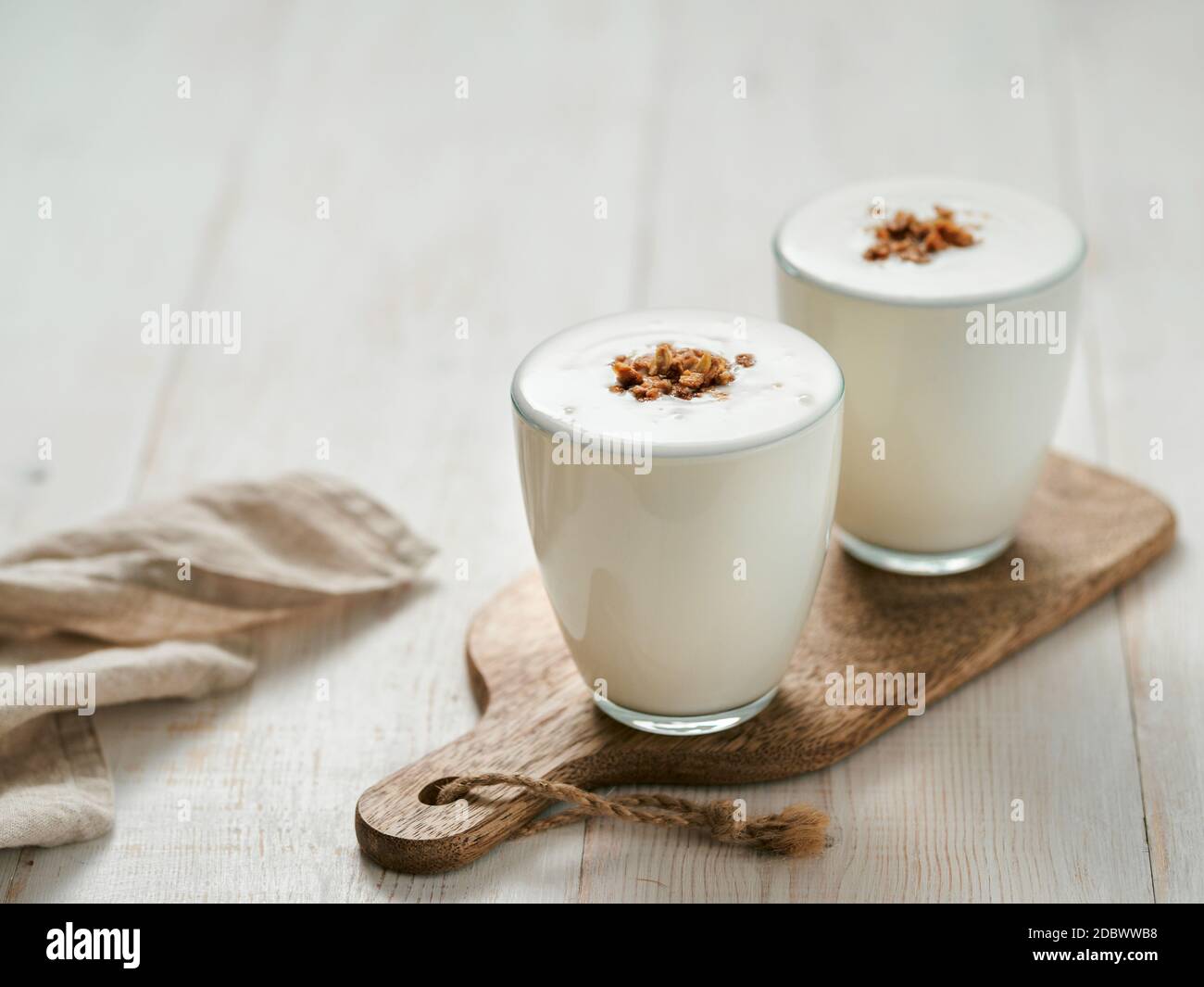 Kefir, latticello o yogurt con muesli. Yogurt in vetro su sfondo bianco di legno. Bevanda casearia fermentata a freddo probiotica. Salute intestinale, prod fermentato Foto Stock