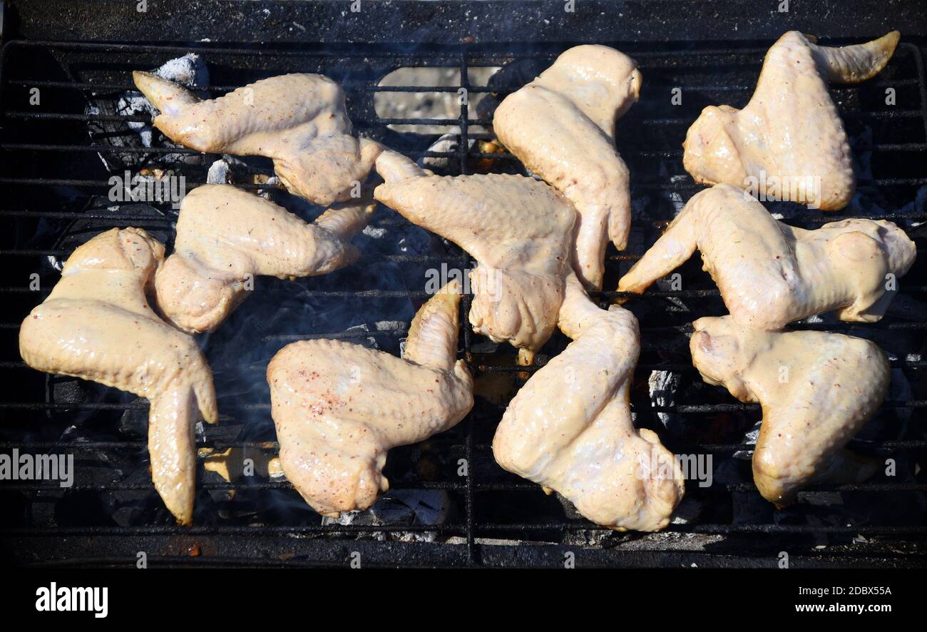Ali di pollo crude marinate in panna acida e spezie, grigliate sulla griglia. Inizia a cucinare, barbecue Foto Stock
