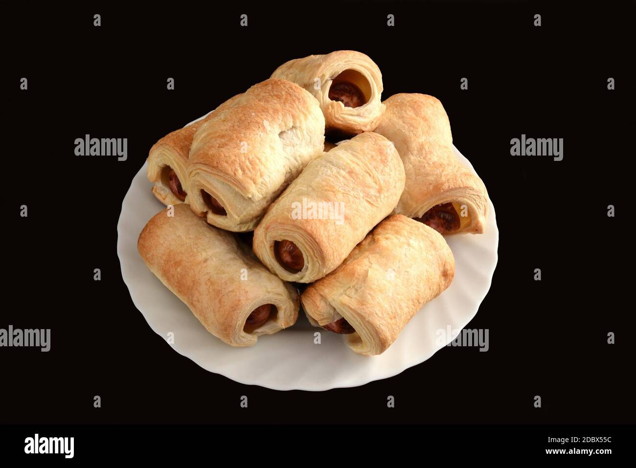 Molti involtini di salsiccia (maiali in una coperta) sulla piastra bianca sul tavolo nero Foto Stock