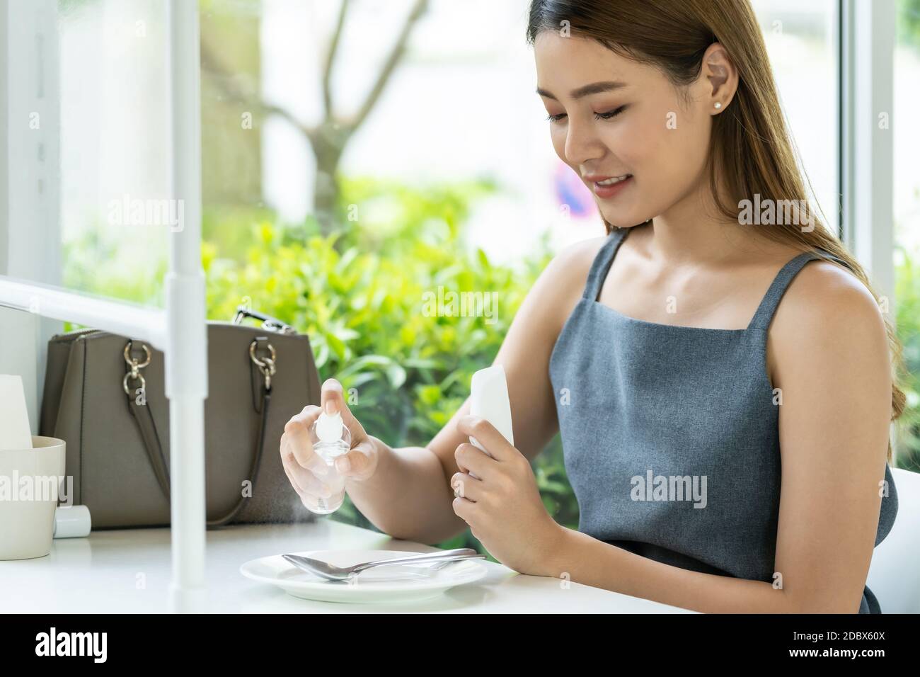 Asian attraente donna spruzzando alcool su stoviglie in ristorante per pulire ridurre l'infezione di coronavirus covid-19. Nuovo stile di vita normale al resta Foto Stock