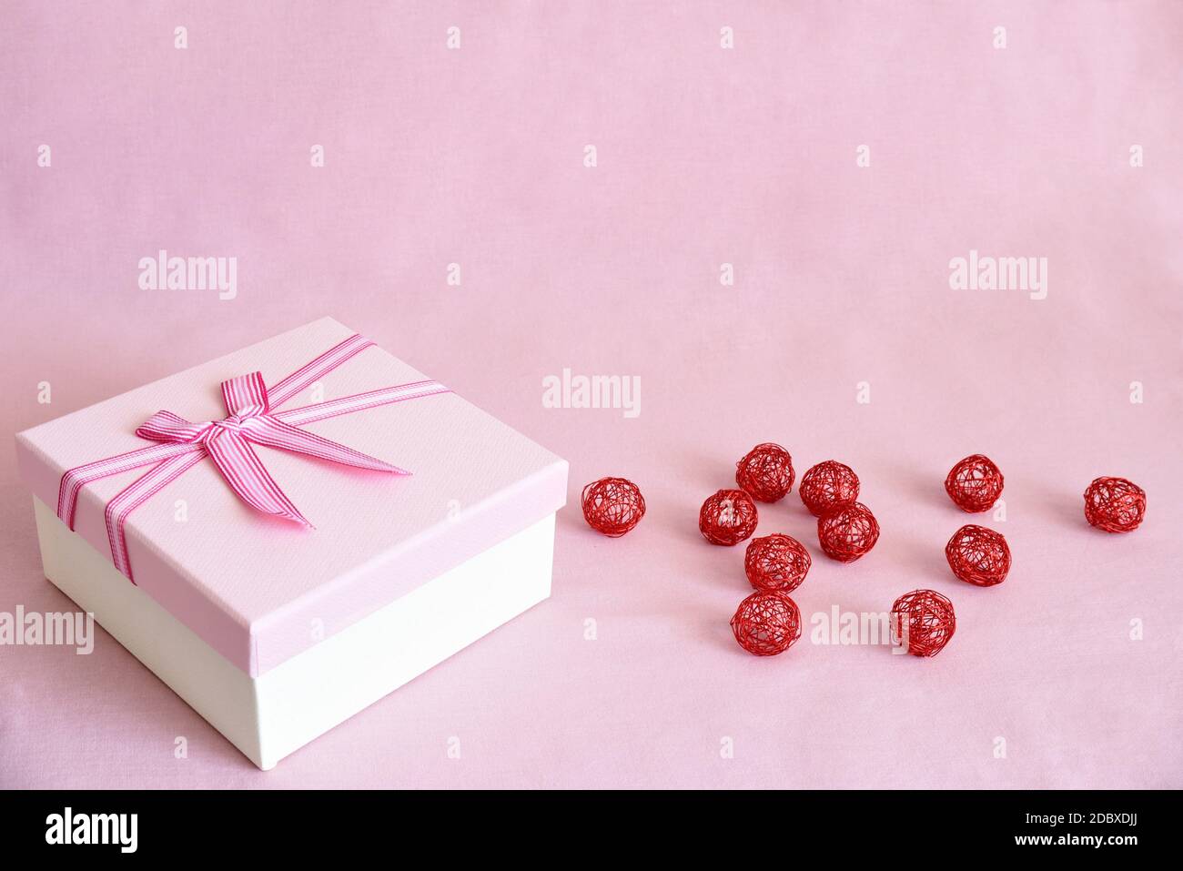 Scatola regalo bianca con coperchio rosa e arco accanto alle palline di  metallo rosso su fondo di tessuto rosa con spazio per la copia. Concetto di  celebrazione Foto stock - Alamy