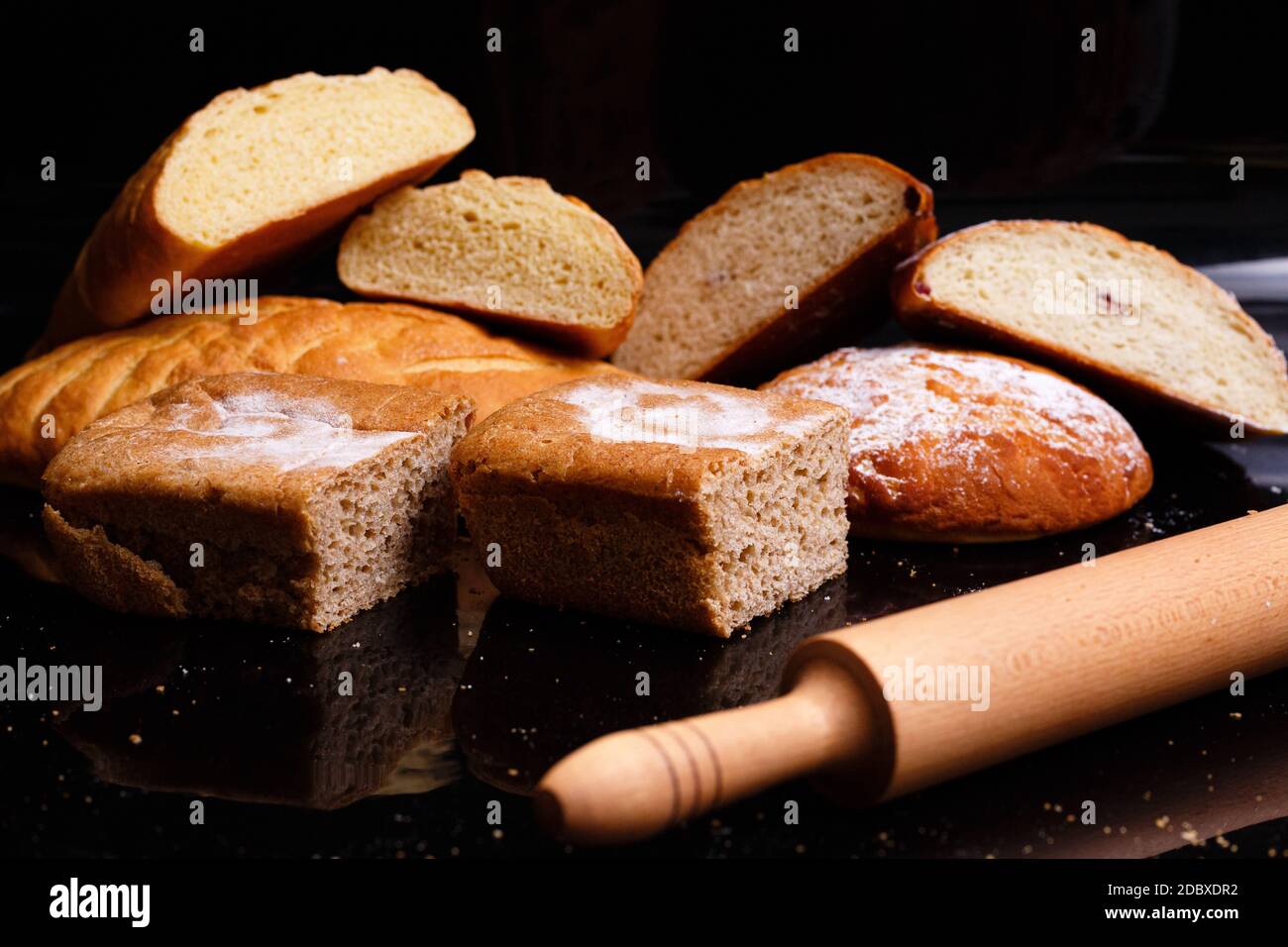 Cottura su fondo nero con una coppiglia. Un sacco di pasticcini e pane. Il pane nel taglio è intero. Foto Stock