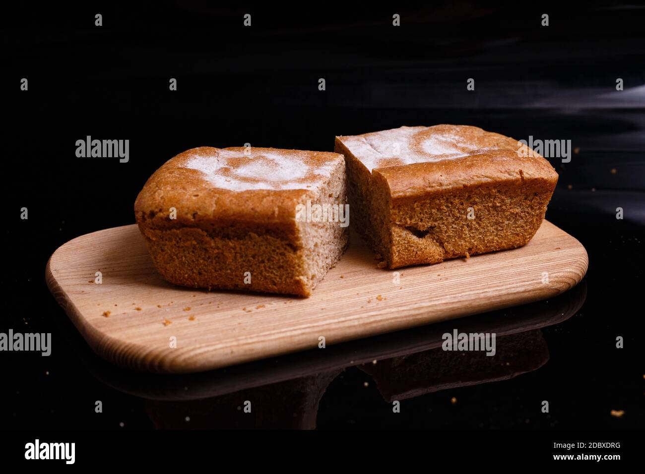 Pane grigio fatto in casa su sfondo nero. Foto nella sezione. Tagliare il pane con un coltello. Foto Stock