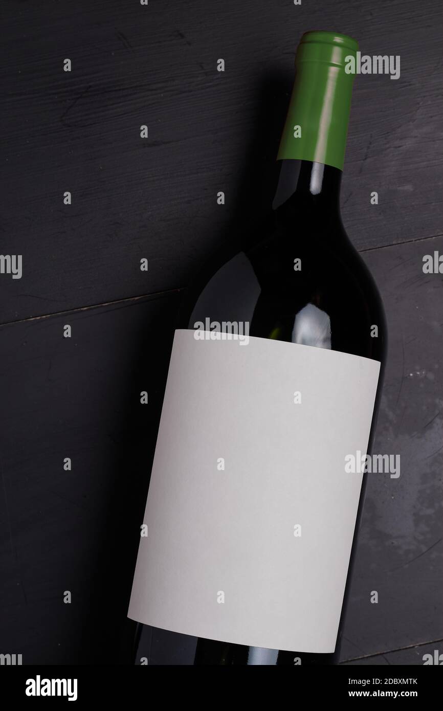 Una bottiglia di vino su un tavolo di legno nero chiuso vista dall'alto con tappo verde Foto Stock