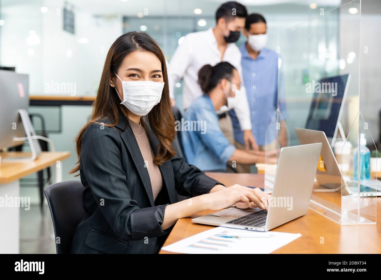 Ritratto di asian Office dipendente businesswoman indossare maschera  protettiva viso lavorare in un nuovo ufficio normale con un team  interracial in background come divist sociale Foto stock - Alamy