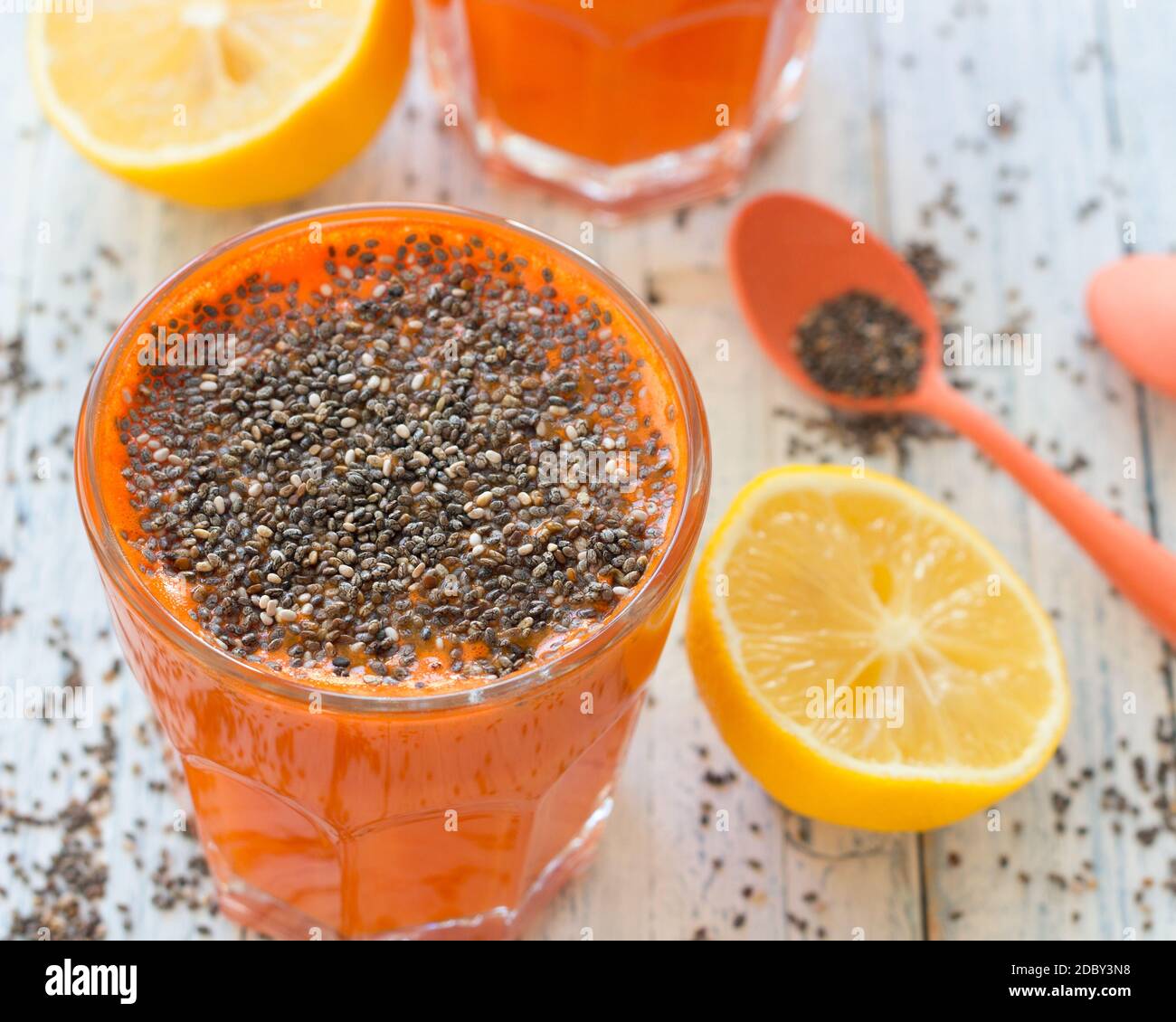 Cocktail di carote con limone e semi di chia in un bicchiere su sfondo azzurro, fuoco selettivo. Bevanda sana e deliziosa Foto Stock