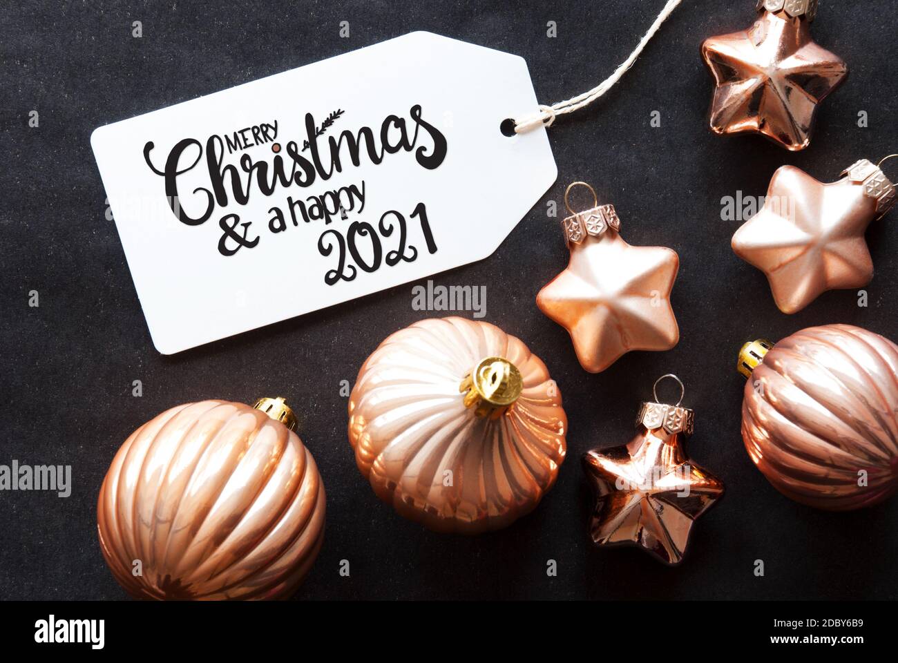 Un'etichetta con la calligrafia inglese buon Natale e UN felice 2021. Golden Ball ornamento su sfondo nero. Foto Stock