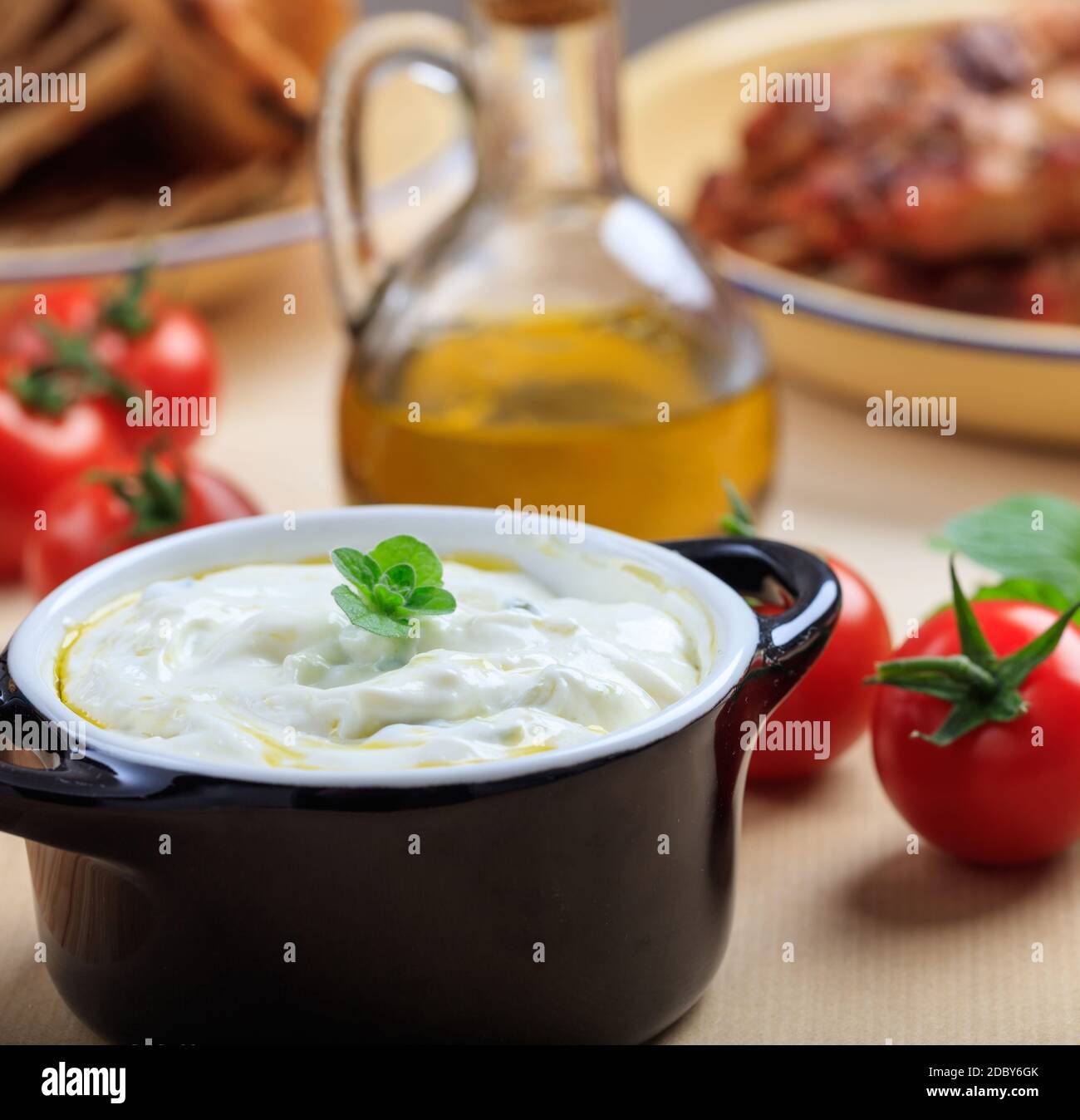 Salsa tzatziki greca. Antipasto tradizionale speziato a base di yogurt greco, cetriolo, olio d'oliva e aglio, servito in una ciotola nera vista guardaroba Foto Stock