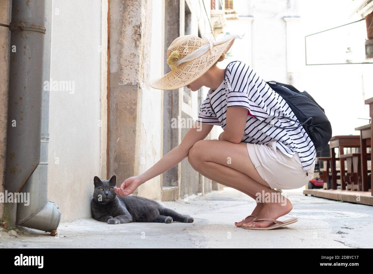 Donna turistica che indossa un grande cappello di paglia in vacanza estiva  in ald tradizionale città mediterranea, squadrando sulla vecchia strada  pedonale in pietra e takin Foto stock - Alamy