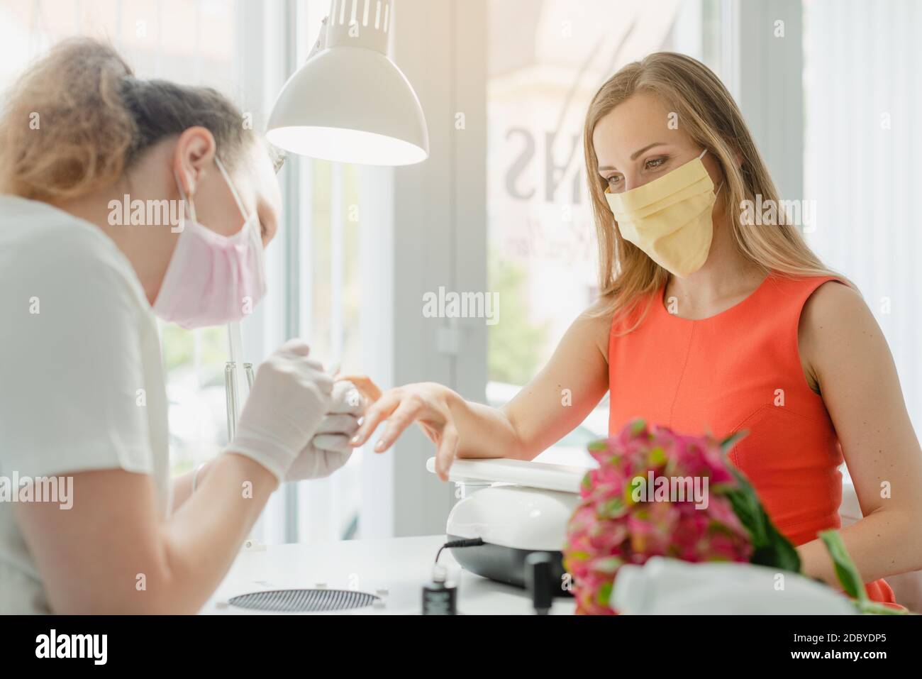 Donna nel salone delle unghie che riceve manicure che indossa una faccia maschera durante la crisi del coronavirus Foto Stock