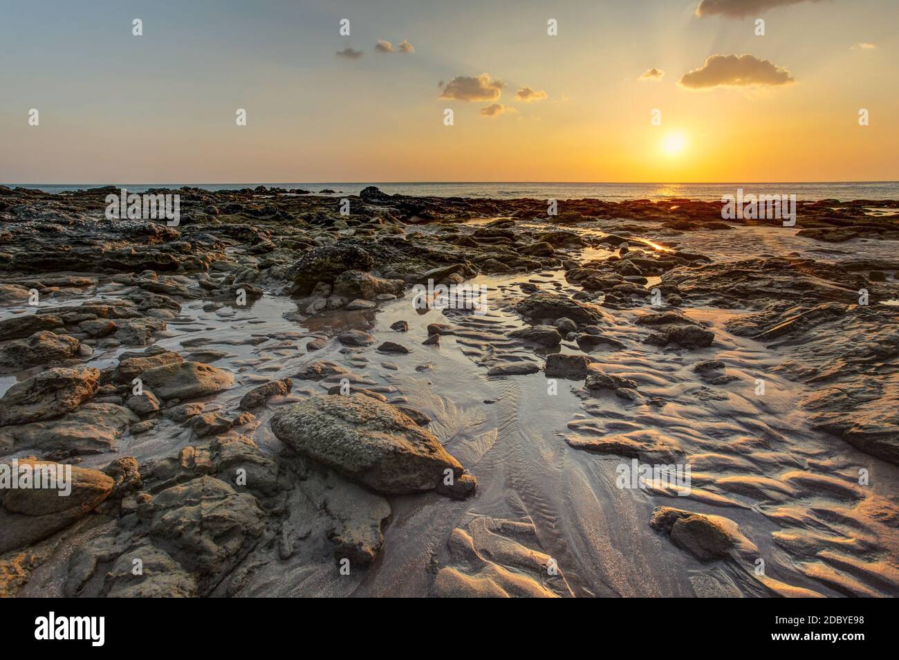 Spiaggia di golden sunset luce durante la bassa marea che mostra le formazioni di sabbia e pietre umido non coperta dal mare. Kantiang Bay, Ko Lanta, Thailandia. Foto Stock