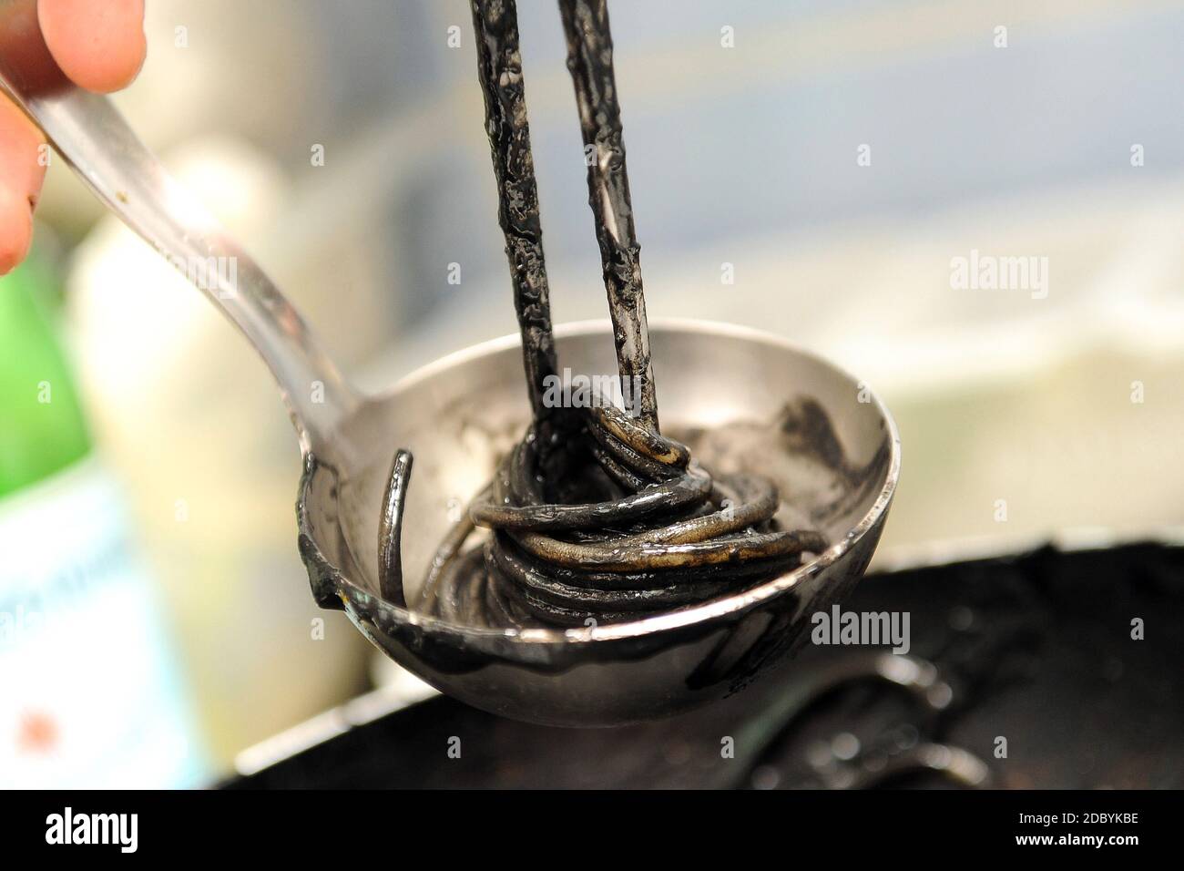 ladle con seppie inchiostro linguine mentre è cucinato dal chef Foto Stock