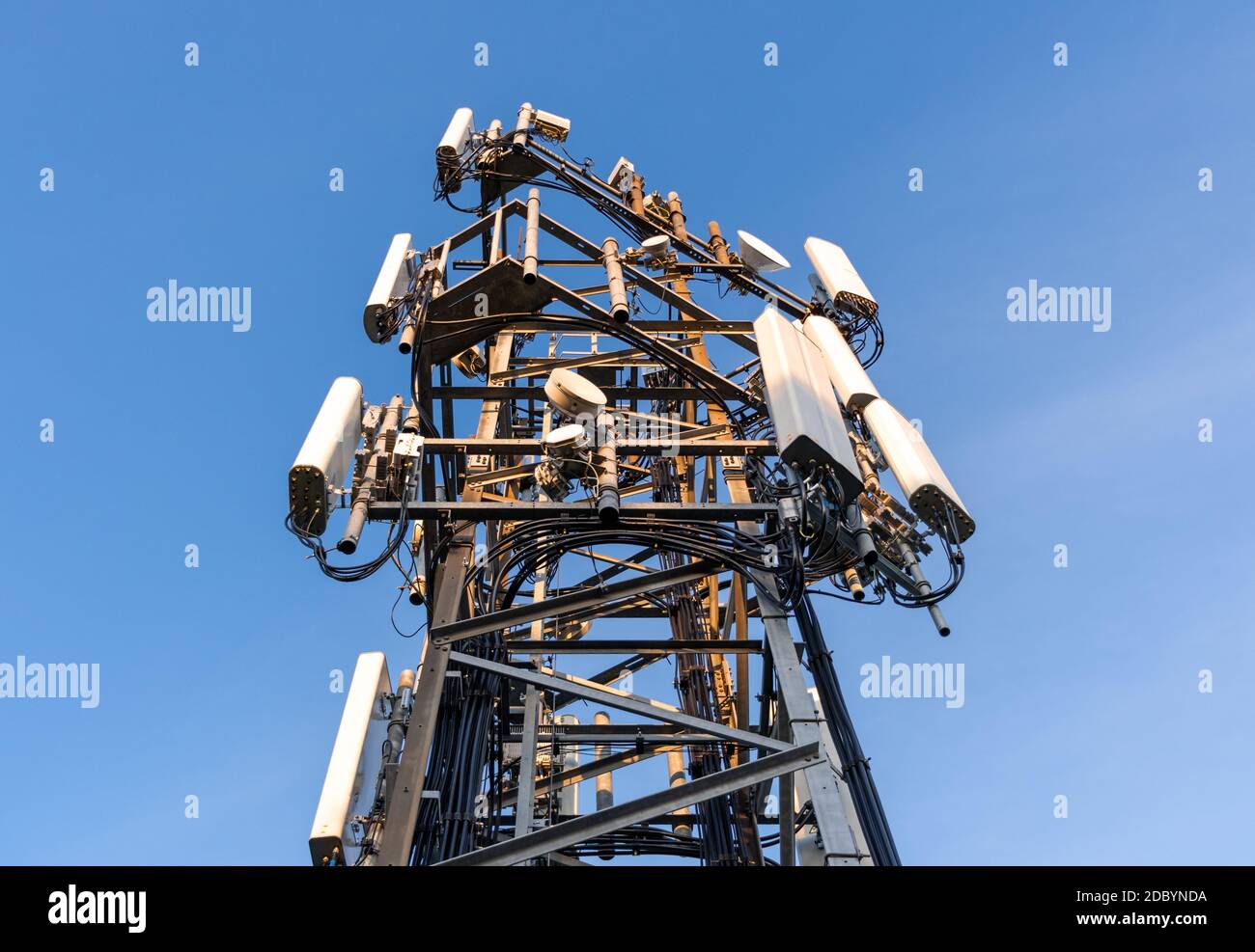 Una torre di comunicazione con antenne di rete cellulare su sfondo blu. Foto Stock