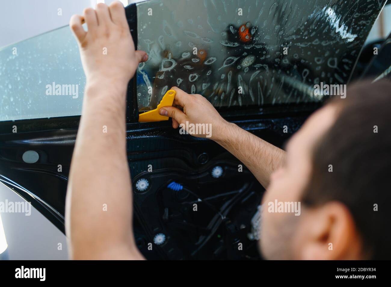 Il lavoratore in officina installa materiale insonorizzante all'interno  della scheda della porta dell'auto. Processo di isolamento acustico per auto  Foto stock - Alamy