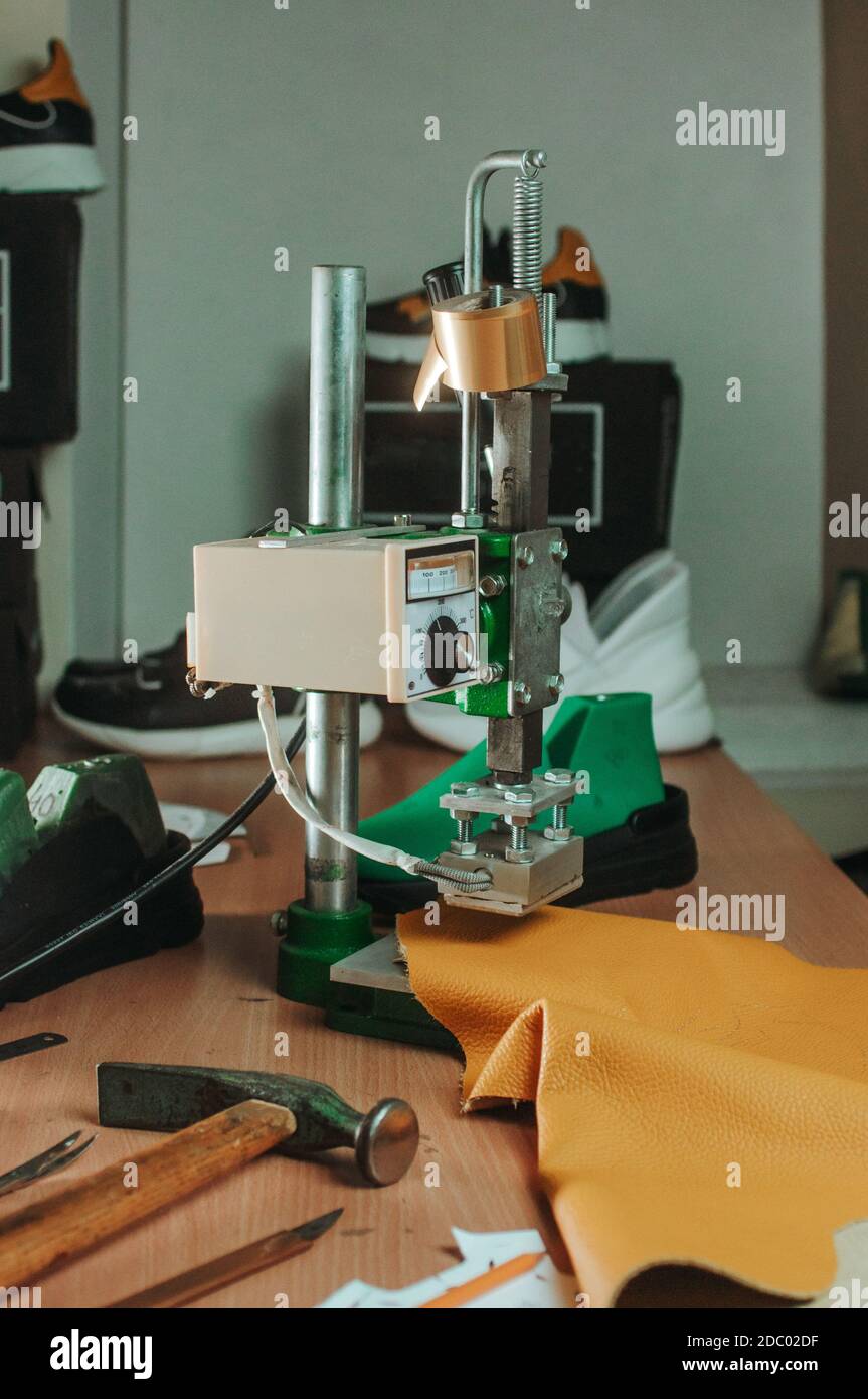 Stampa del timbro che fa un timbro su una pelle in officina del calzolaio. Foto Stock