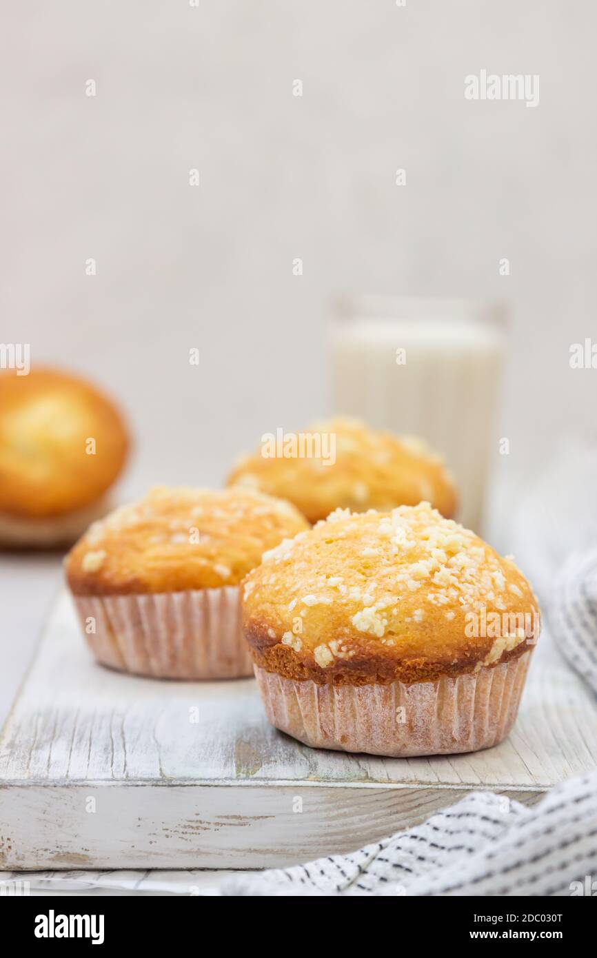 Muffin alla vaniglia e muffin con streusel in tazze di carta e un bicchiere di latte. Colazione o snack per bambini. Foto Stock