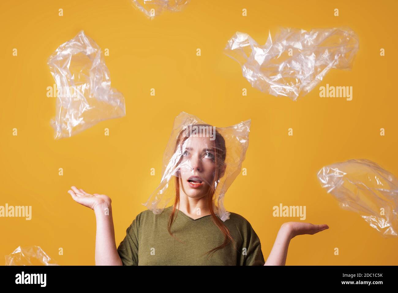 giovane donna sopraffatta da rifiuti di plastica e soffocante di plastica borsa sopra la sua testa - ecologia e concetto di inquinamento Foto Stock
