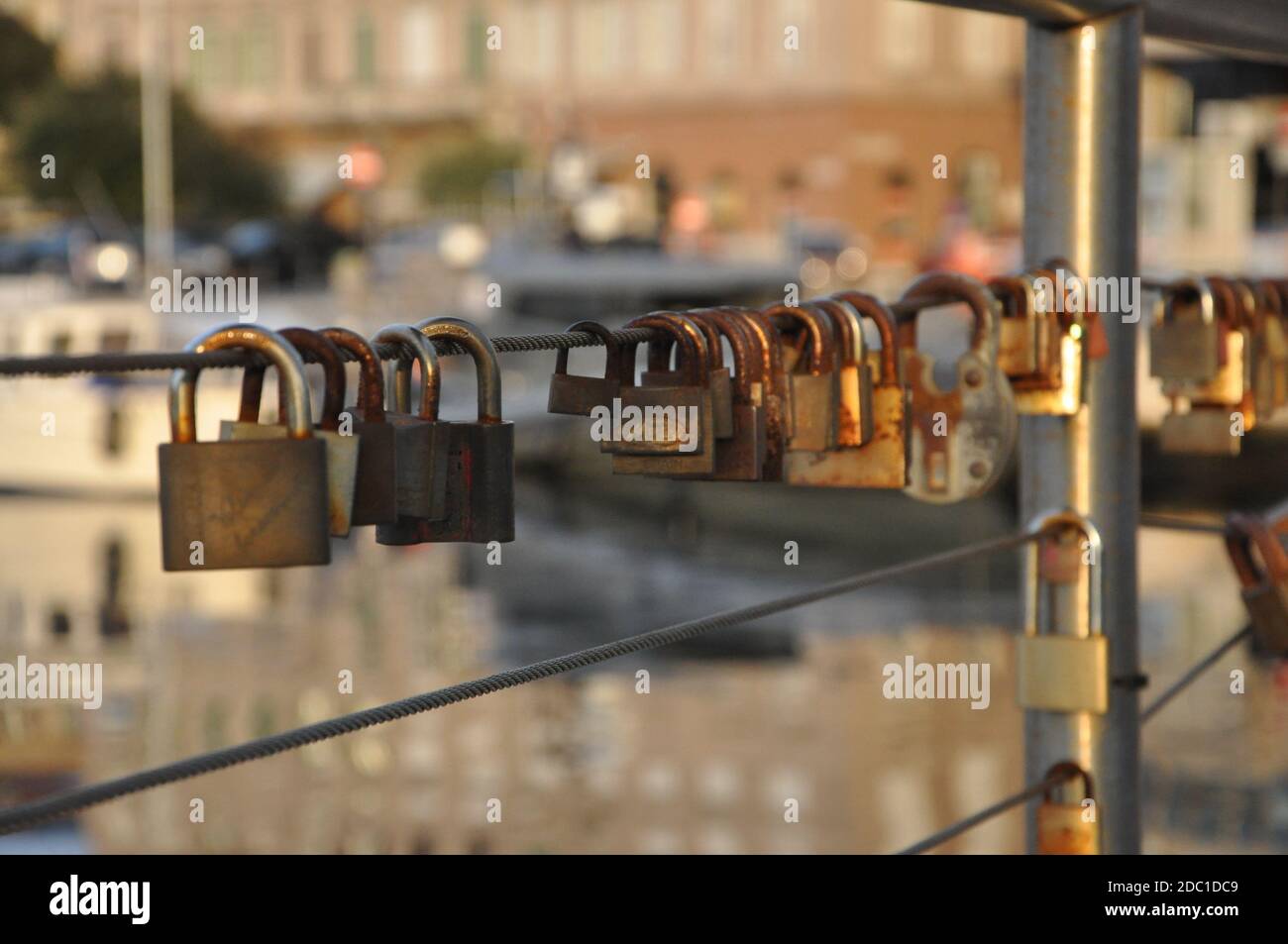 Lucchetti d'amore arrugginiti appesi su un filo di ferro sul mare background.Many lucchetti di amanti appesi su ringhiere ponte. Foto Stock