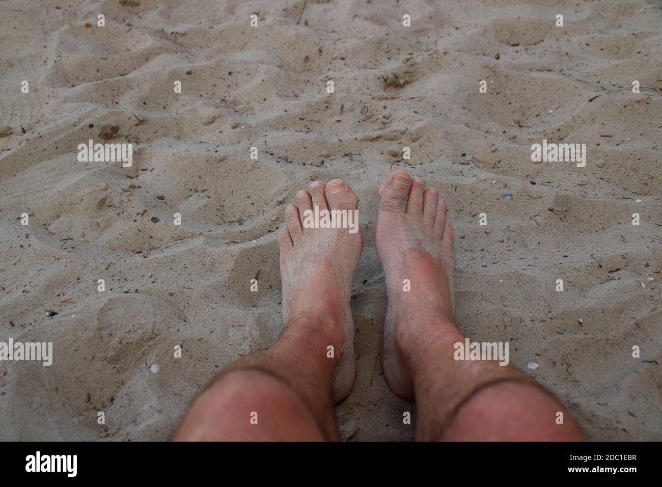 I piedi su una spiaggia di sabbia sono coperti di sabbia Foto Stock