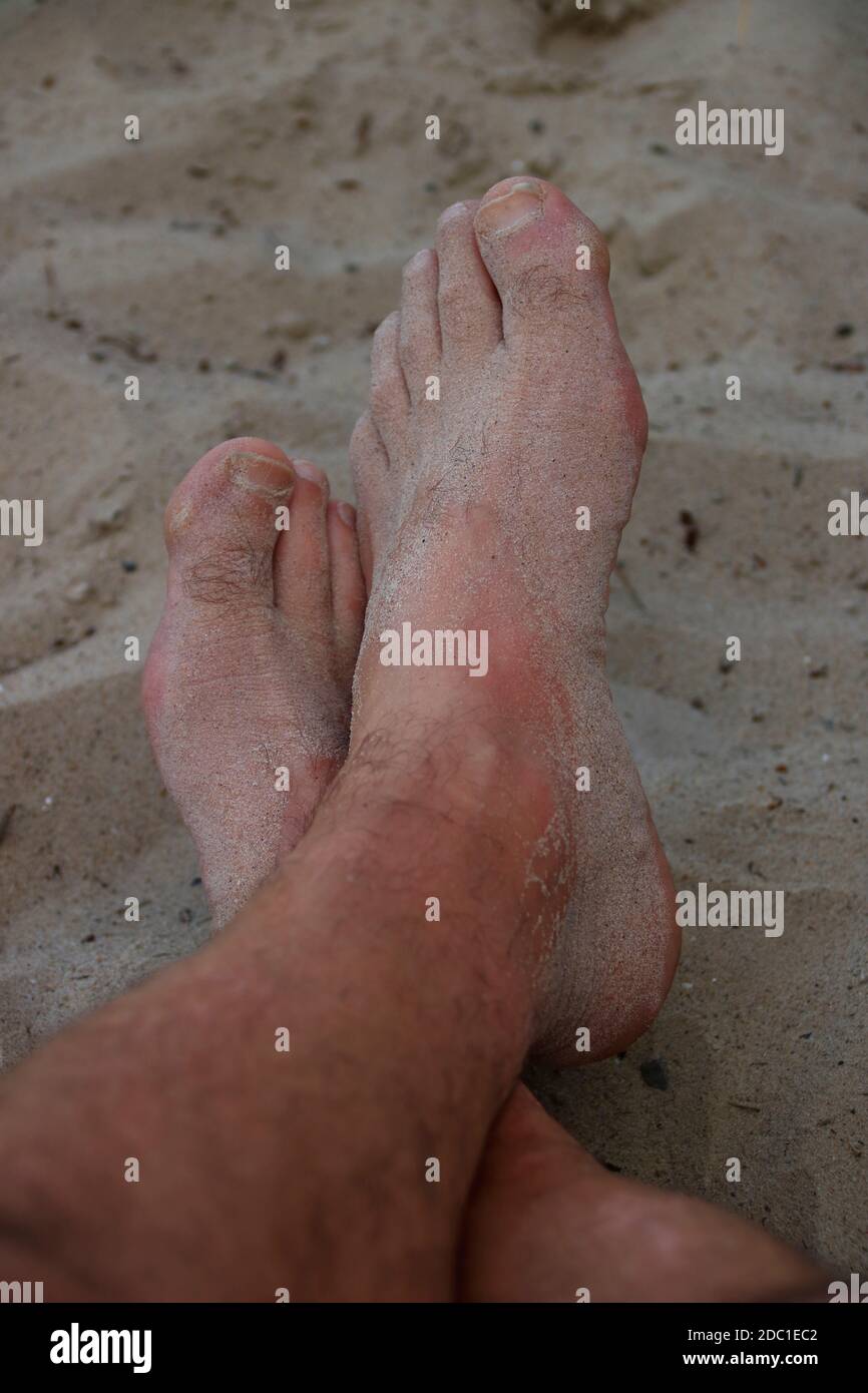 I piedi su una spiaggia di sabbia sono coperti di sabbia Foto Stock
