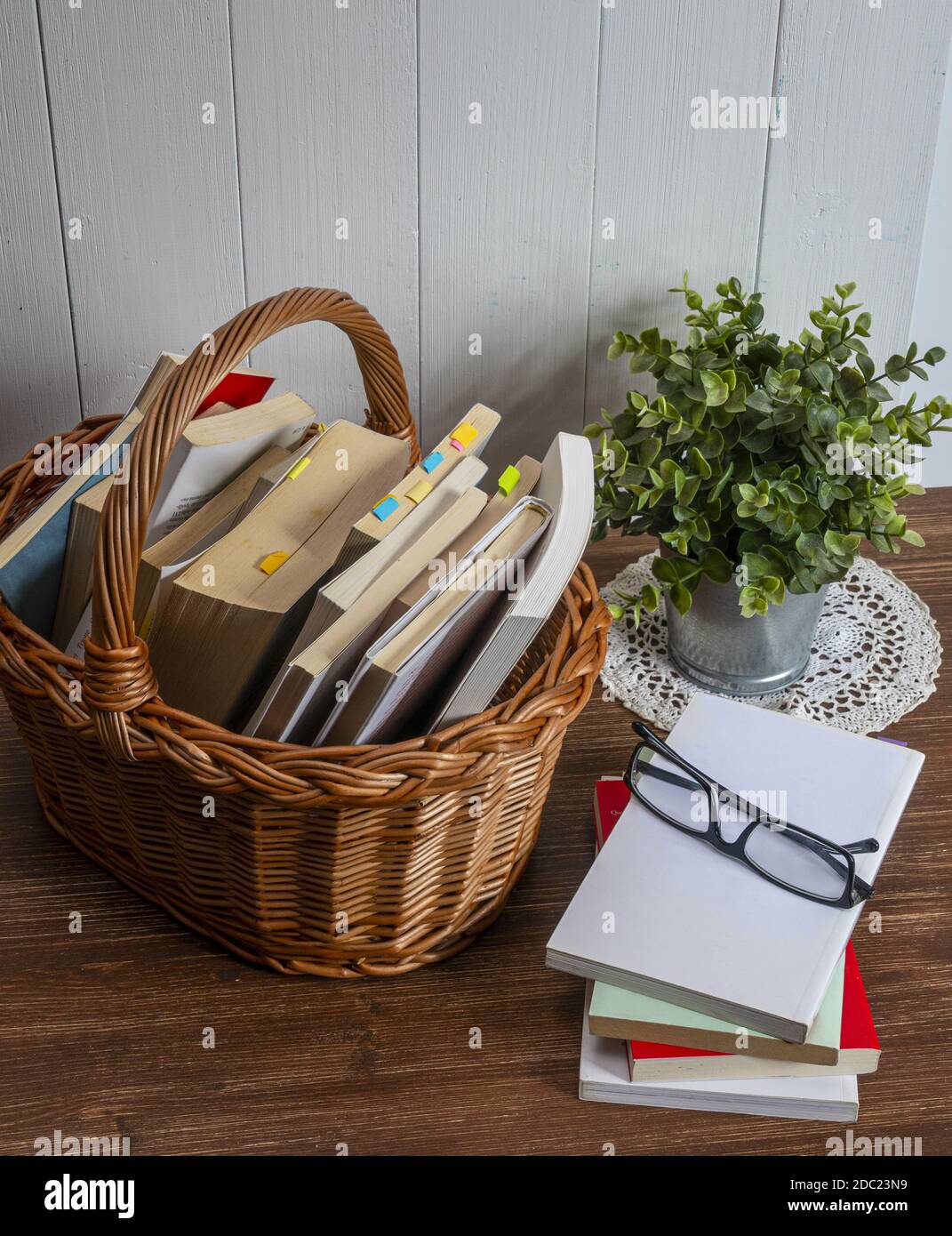 un cesto di vimini con alcuni libri su un tavolo di legno Foto stock - Alamy