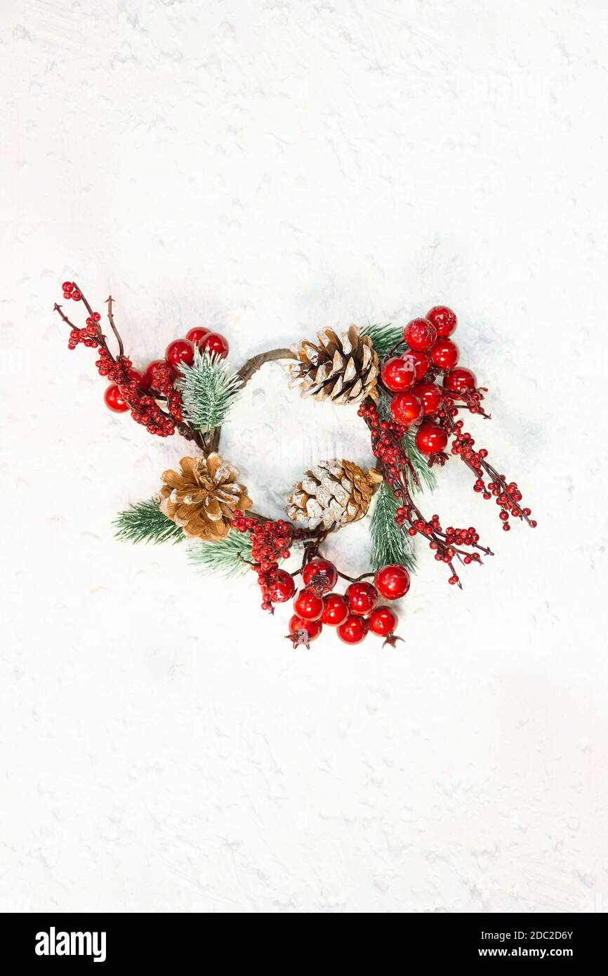 Bacche rosse con rami di abete e coni. Corona di Natale su sfondo bianco con neve. Carta anno nuovo. Spazio di copia Foto Stock