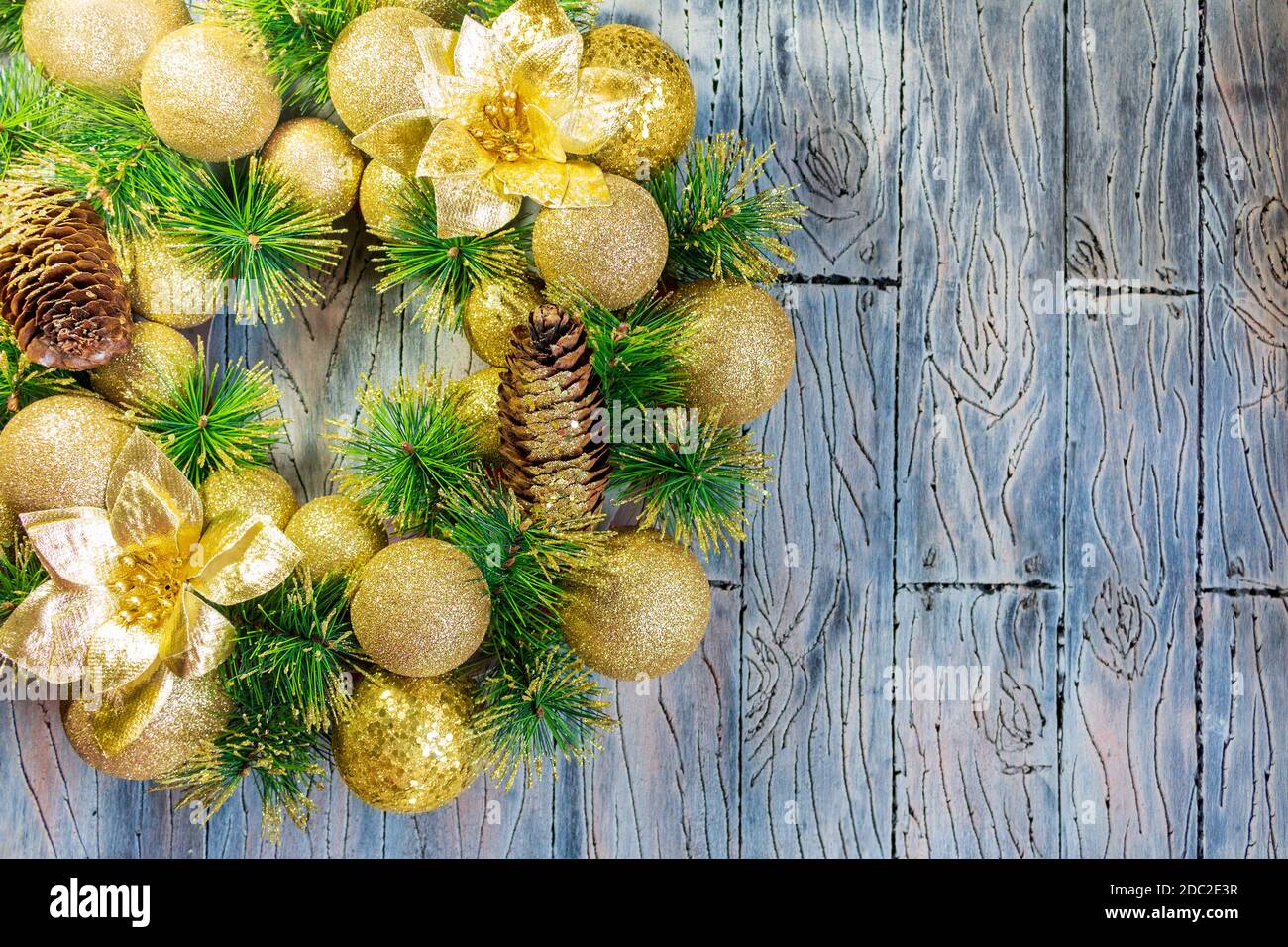 Palline di Natale gialle lucenti e cono con chiodi e rami di pino su fondo di legno grigio blu. Carta anno nuovo Foto Stock