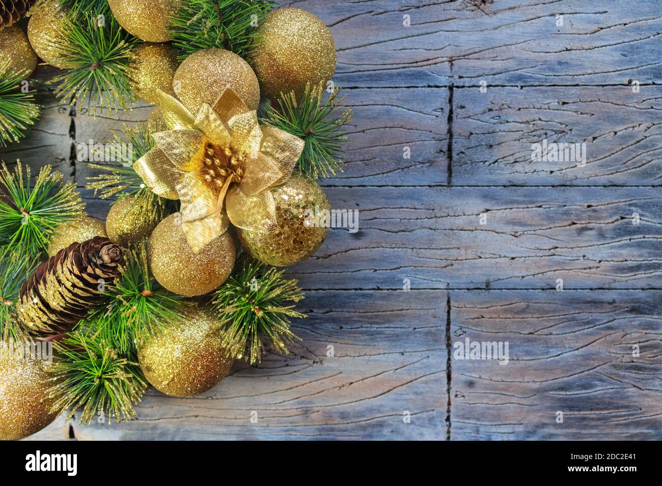 Palline di Natale gialle lucenti e cono con chiodi e rami di pino su fondo di legno grigio blu. Carta anno nuovo Foto Stock