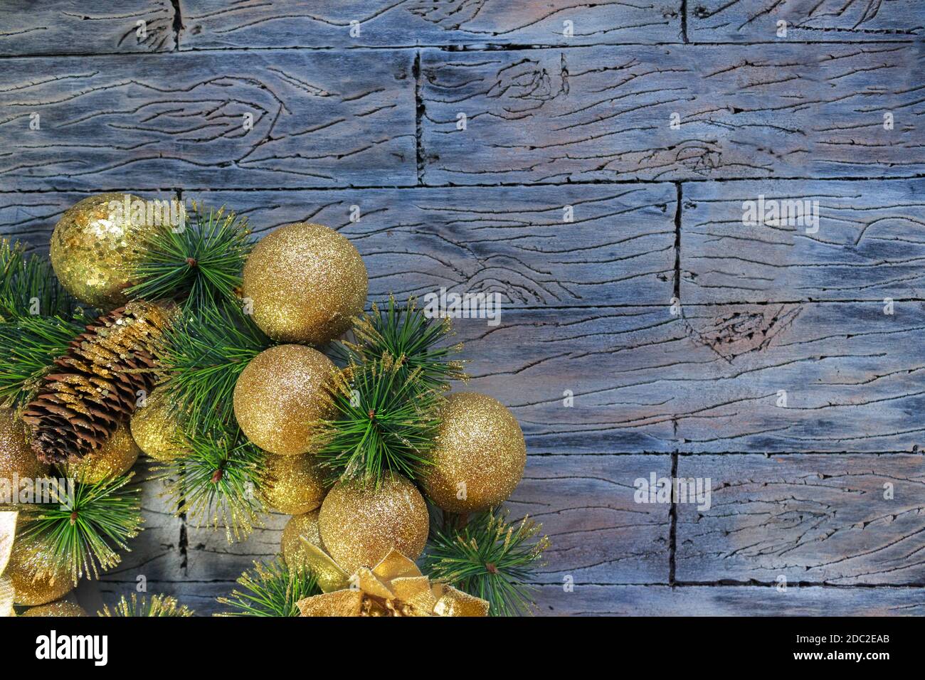 Palline di Natale gialle lucenti e cono con chiodi e rami di pino su fondo di legno grigio blu. Carta anno nuovo Foto Stock