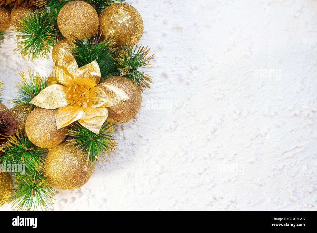 Palline di Natale gialle lucenti e cono con chiodi e rami di pino su sfondo bianco. Carta anno nuovo Foto Stock