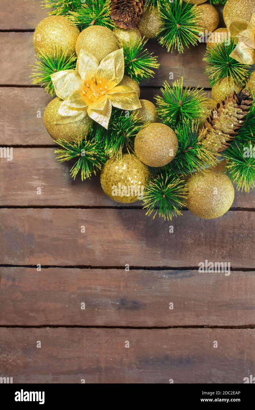 Palline di Natale gialle lucenti e cono con chiodi e rami di pino su tavole di legno marrone sfondo. Carta anno nuovo Foto Stock