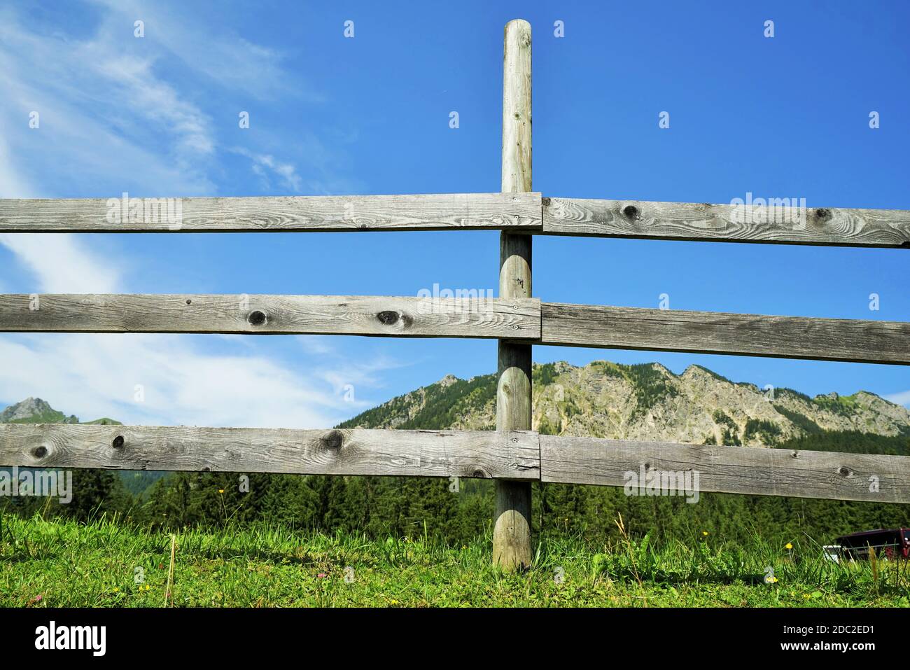 Recinzione in legno nelle Alpi sotto il cielo blu Foto Stock