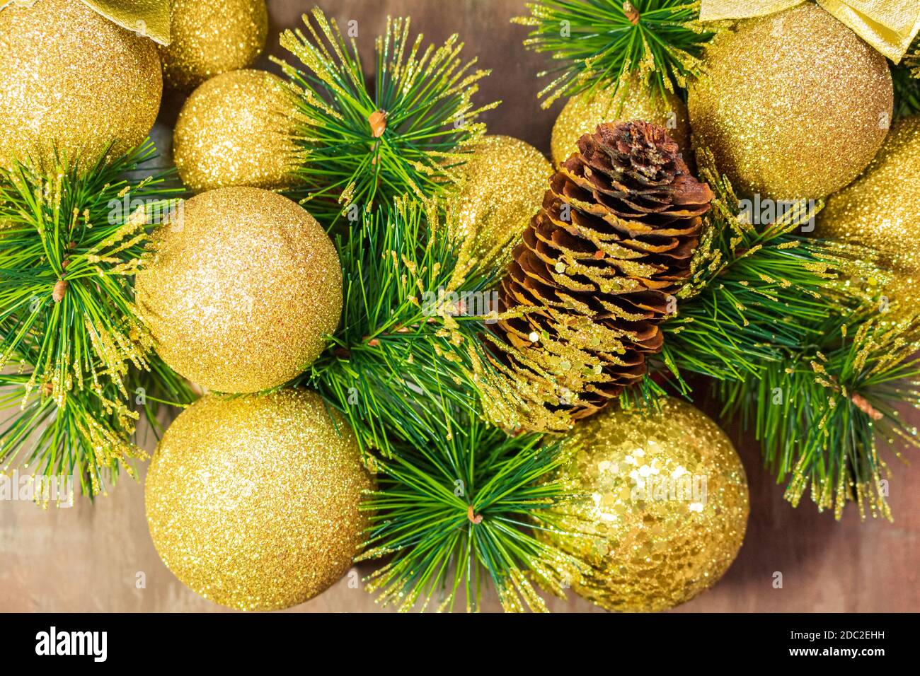 Palline di Natale giallo brillante e cono con chiodi e rami di pino su sfondo di legno. Carta anno nuovo Foto Stock