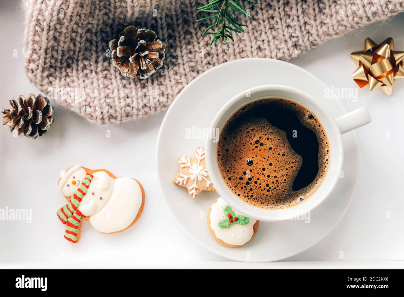 Una tazza di caffè con pan di zenzero, un ramo di abete rosso, coni di pino e un plaid lavorato a maglia. Concetto di Capodanno e di Natale. Vista dall'alto, disposizione piatta. Foto Stock