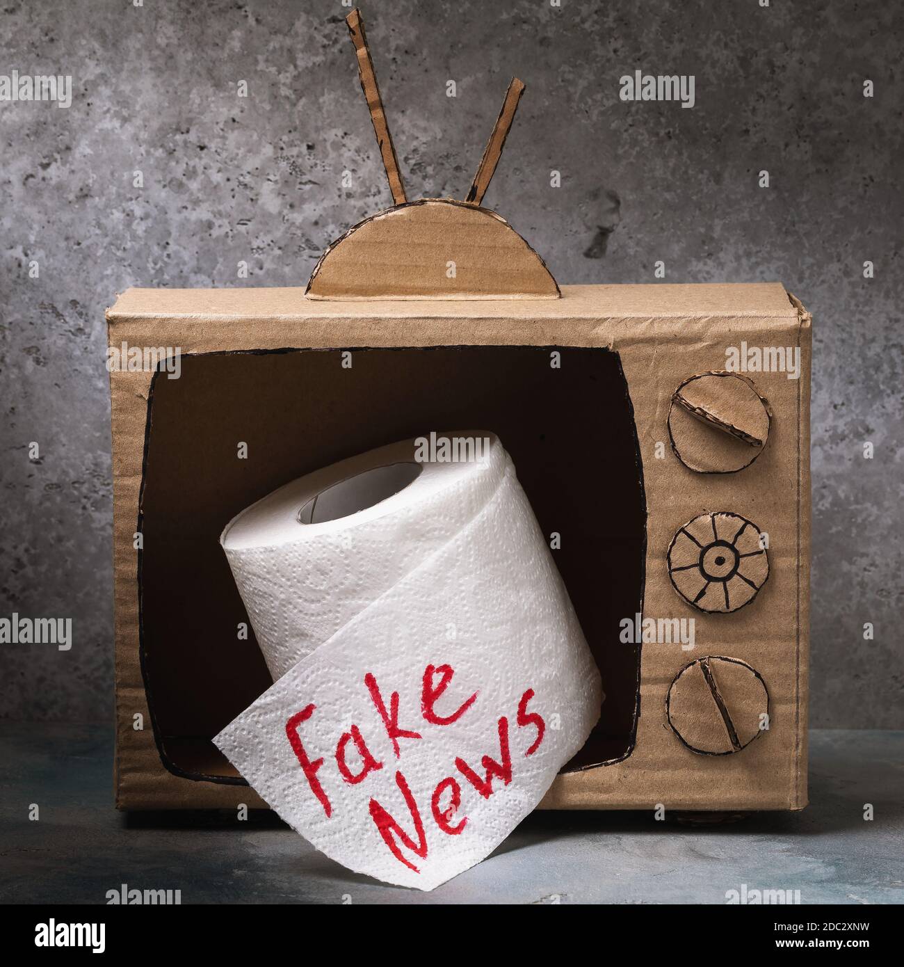 Un modello di TV in cartone con un rotolo di carta igienica che fuoriesce dallo schermo. Concetto di notizie false Foto Stock