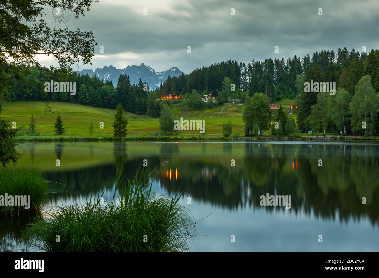 Capanne in legno sul lago e catena montuosa Kaiser sullo sfondo di Schwarzsee vicino a Kitzbuhel, Austria, Europa Foto Stock