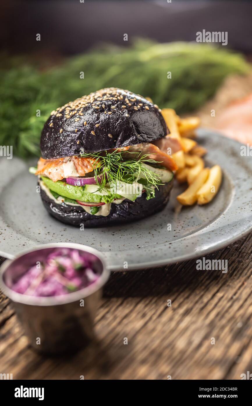 Hamburger nero salmone farcito avocado e insalata di cetrioli con patatine fritte Foto Stock