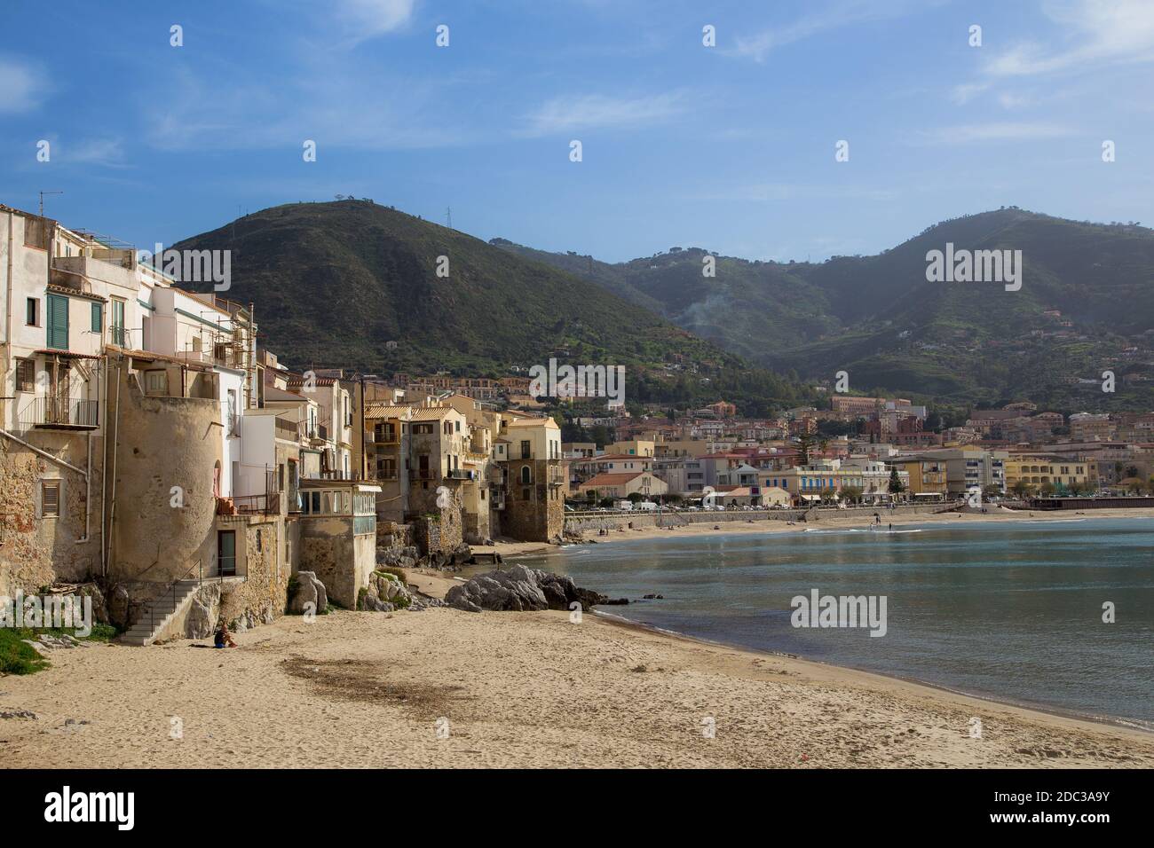 Céfalu, Sicilia, Italia - 16 Marzo 2018: una rilassante giornata di sole sulla spiaggia di Céfalu, con poche persone irriconoscibili e vecchi edifici tipici Foto Stock