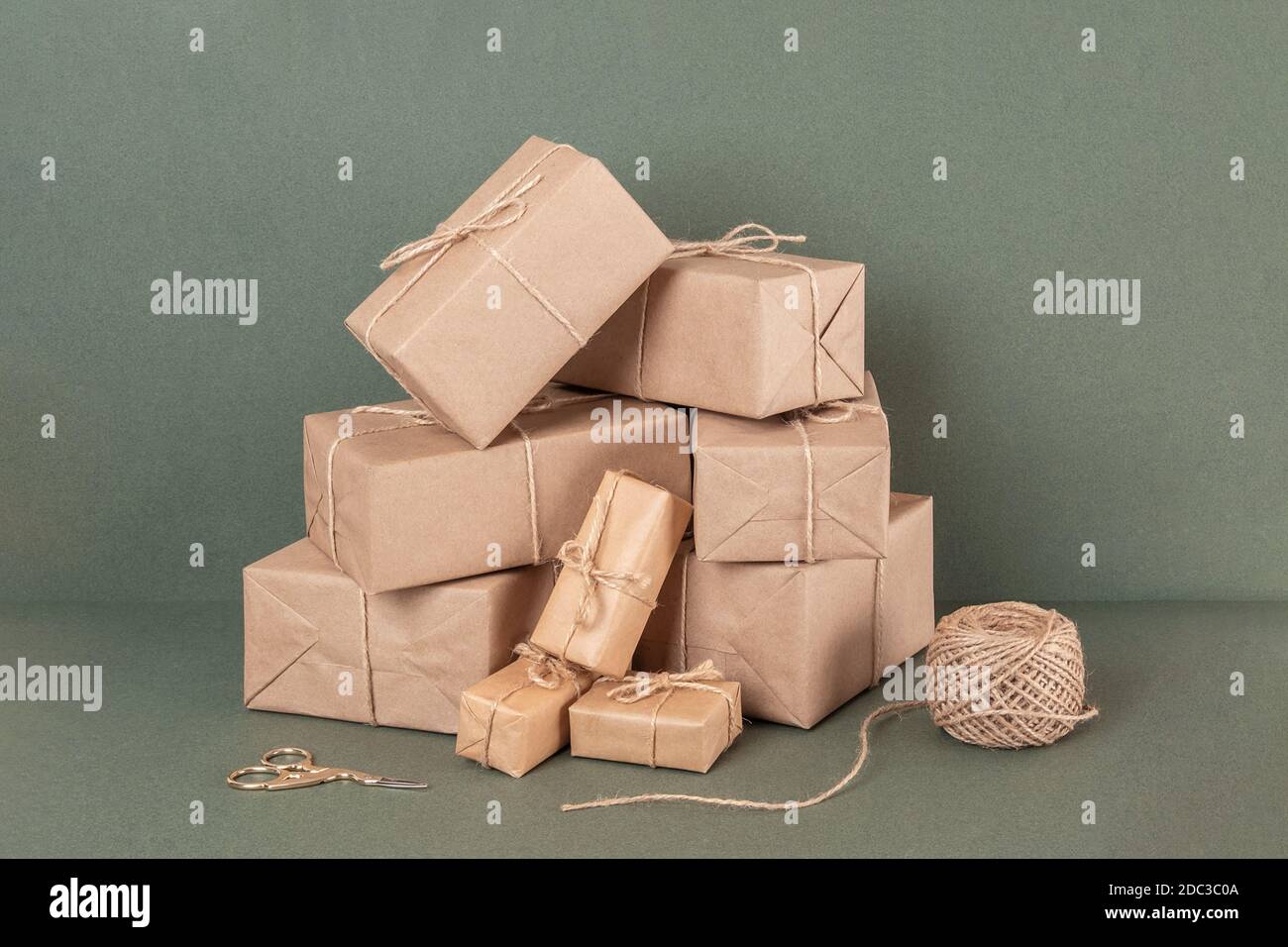 Scatole in carta artigianale, spago e forbici su sfondo verde. Concept NATALE o Capodanno, Zero Waste Buon Natale. Vista frontale. Foto Stock