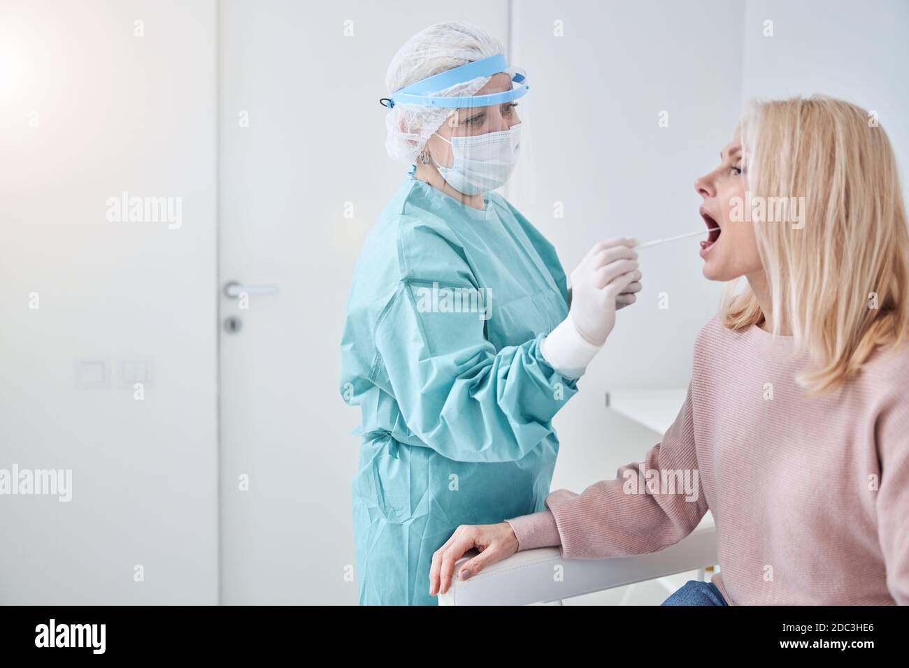 Tecnico di laboratorio qualificato che ingera la gola del paziente Foto Stock