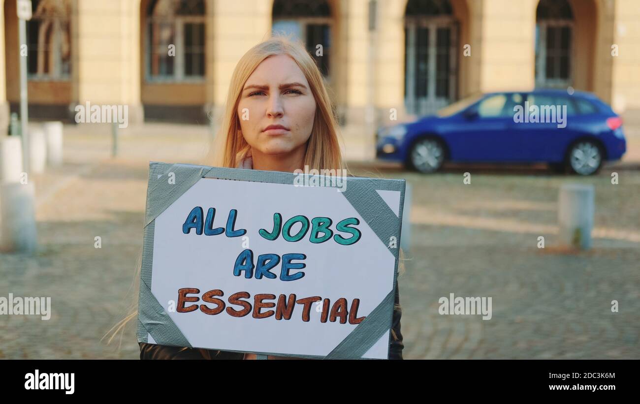 In segno di protesta, la donna di marzo richiama l'attenzione sull'importanza di tutti i tipi di posti di lavoro. Lei tenendo banner e camminando per strada. Foto Stock