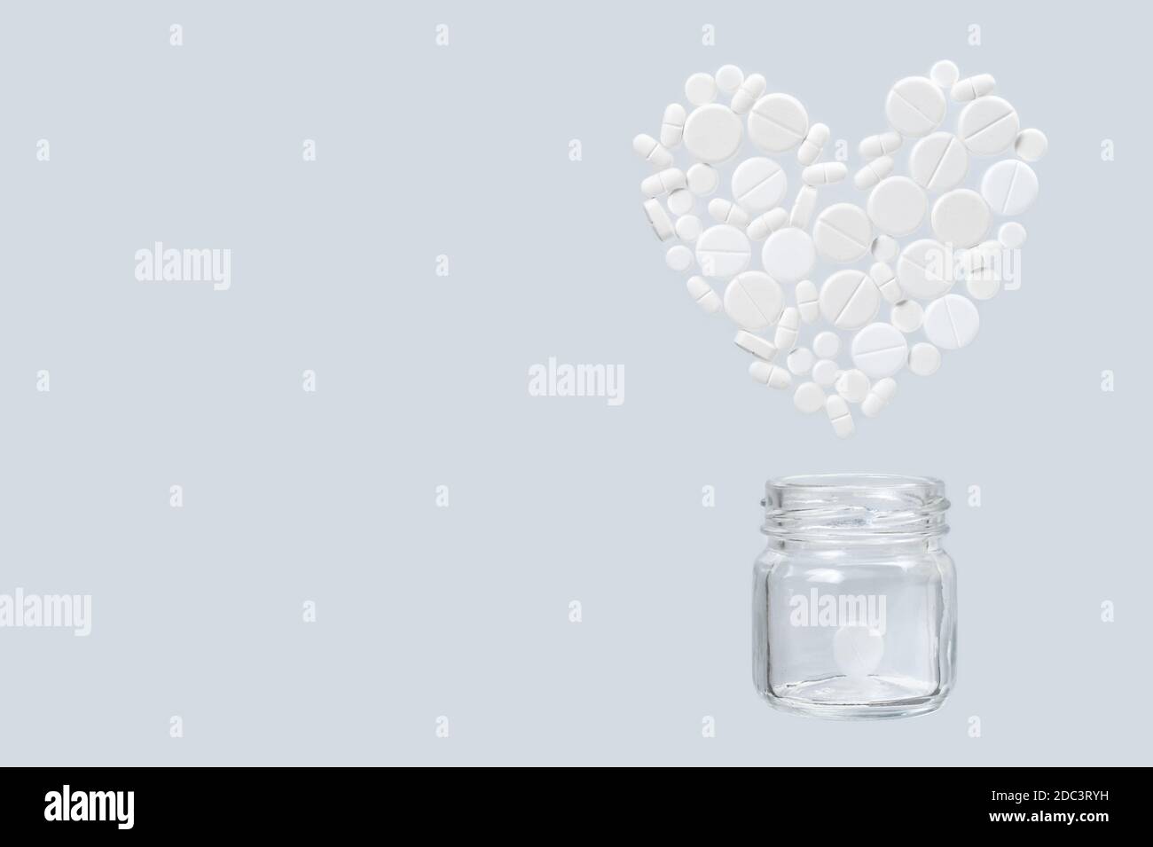 Diverse pillole mediche bianche a forma di cuore volare fuori da un vaso di vetro Foto Stock