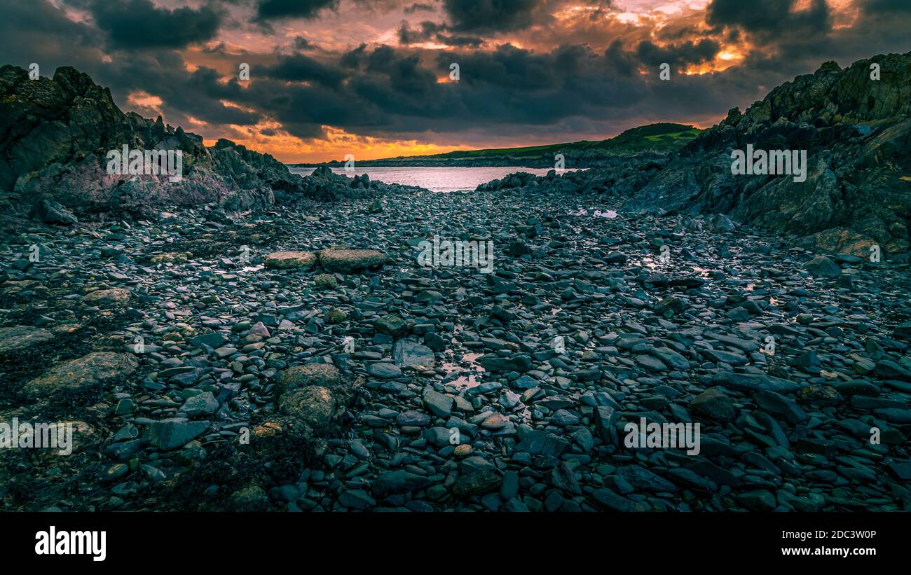 Isola del porto di Whithorn adagiato in un tramonto spettacolare, acqua still e sunburst, spiaggia rocciosa, scogliere Foto Stock