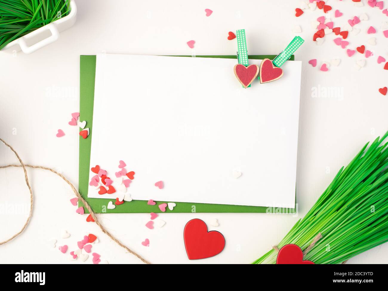 Busta rosa, bouquet verde e cuori su sfondo chiaro. Foto Stock