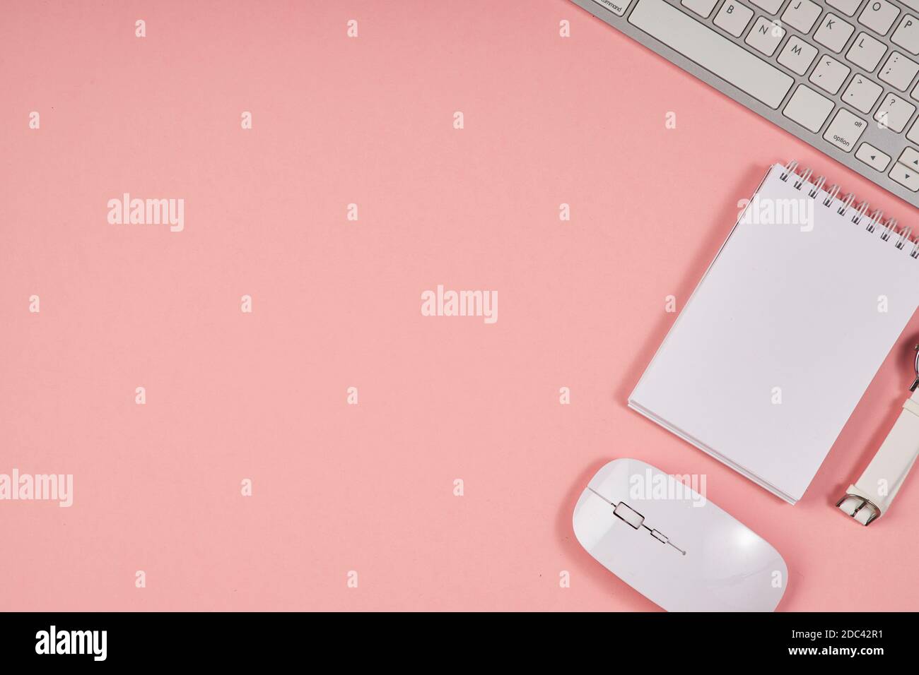 Desktop da ufficio rosa. Tavolo per la vista dall'alto con blocco note e tastiera. Fock up, spazio di copia. Foto Stock