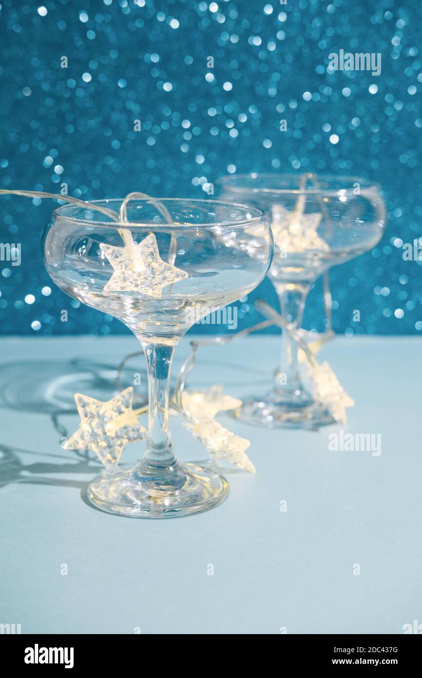 Natale sfondo festivo minimo con stelle garland in bicchieri di champagne. Astratto Natale e Capodanno colore glitter sfondo blu lucido ai Foto Stock