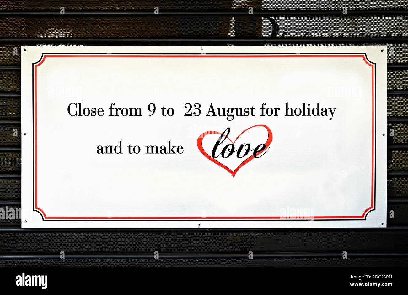 Chiuso in vacanza e per fare l'amore, scritto su un cartello su un otturatore chiuso di un negozio. Vacanze estive. Foto Stock